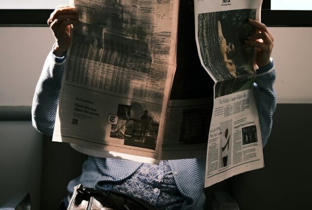 Persona leyendo el periódico junto a una taza de café